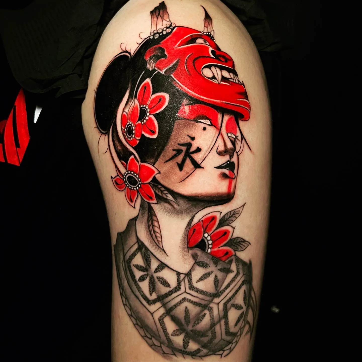 Black and grey geisha portrait tattoo with red accents on shoulder and chest